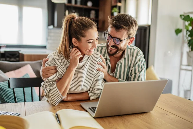 Stage-Image - Paar-lacht-vor-Laptop-Online-Sparen