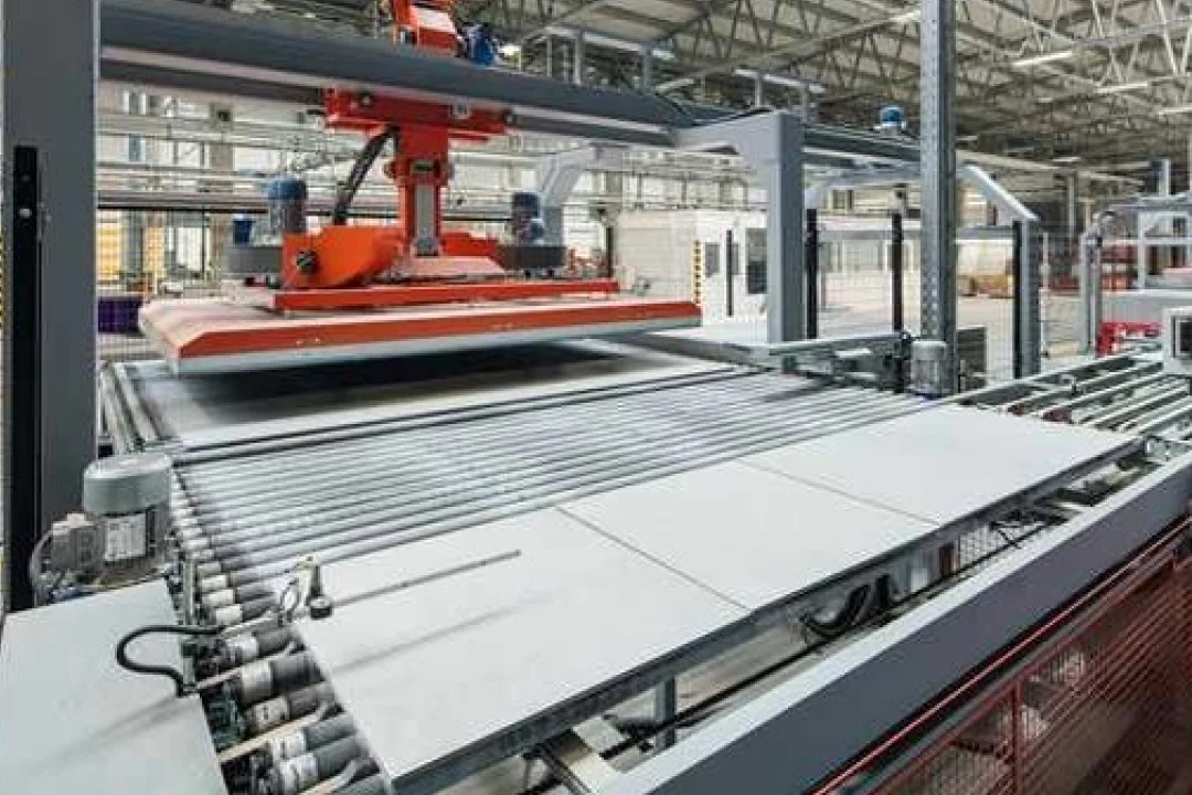 Ein modernes industrielles Fördersystem zur Fliesenherstellung in einer Fabrik. Das Bild zeigt einen roten Roboterarm, der Fliesen auf einem Rollenförderer transportiert. Die Umgebung ist eine geräumige, gut beleuchtete Industriehalle mit sichtbaren Maschinen und Bauelementen.