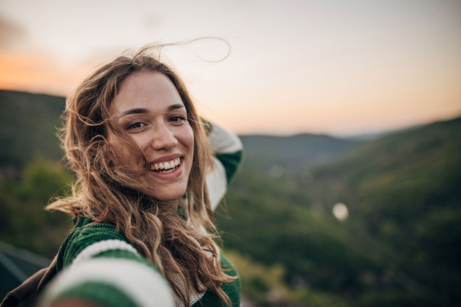 Lachende Frau macht ein Selfie in den Bergen