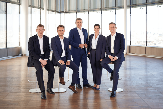 Vorstandsfoto eines fünfköpfigen Teams in einem modernen Büro.