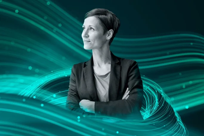 Eine Person steht selbstbewusst mit verschränkten Armen vor einem dynamischen, türkisfarbenen digitalen Wellenhintergrund. Die Szenerie vermittelt eine moderne und technologische Atmosphäre mit fließenden Linien und leuchtenden Akzenten. Das Bild strahlt Professionalität und Innovationsgeist aus und unterstreicht Zukunftsorientierung und Kreativität.