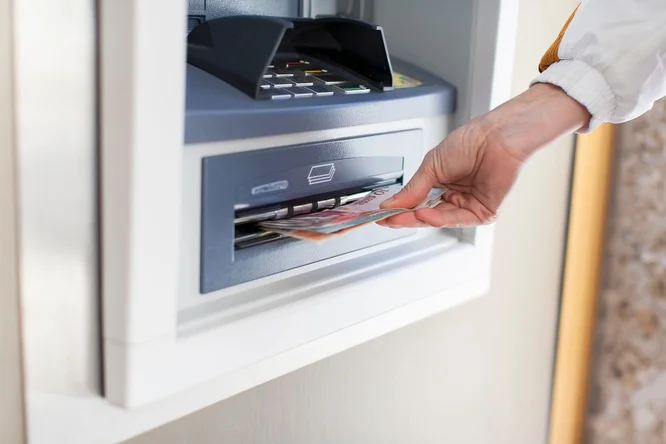 Person hebt geld von einem Bankomaten ab