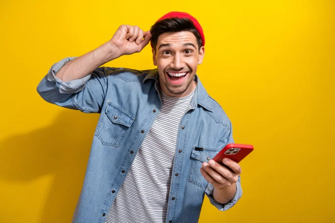 Photo of positive funky guy wear denim jacket chatting apple iphone samsung modern device isolated yellow color background.