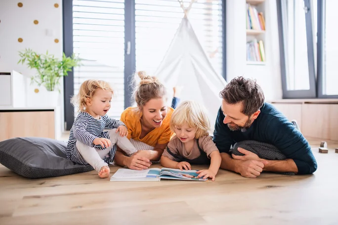 Familie liest gemeinsam im gemütlichen Wohnzimmer