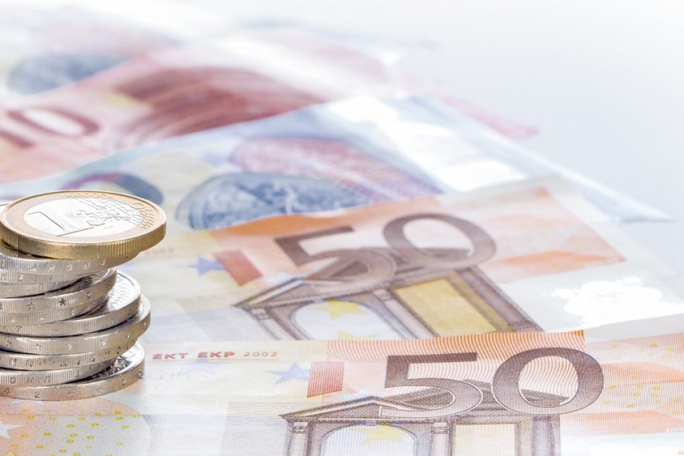 A detailed view of Euro currency featuring €50 banknotes and stacked coins. The image highlights financial elements with a focus on European monetary design. The setting is clean and minimal, emphasizing the currency's details and texture.