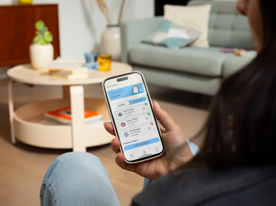 Frau hält Handy in der Hand mit dem Raiffeisen Junior Display