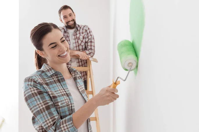 Paar streicht Wand mit grüner Rolle