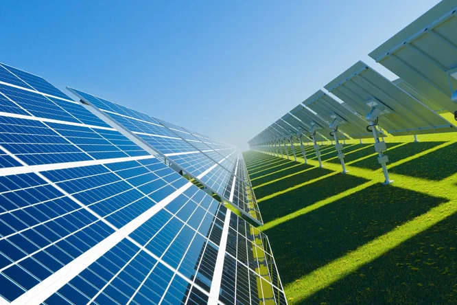 Eine Reihe von Solarmodulen steht auf einer grünen Wiese unter strahlend blauem Himmel. Die Module sind so ausgerichtet, dass sie die Sonneneinstrahlung optimal nutzen und so die Technologie erneuerbarer Energien eindrucksvoll demonstrieren. Helles Sonnenlicht und Schattenspiel unterstreichen die saubere und nachhaltige Energiequelle.