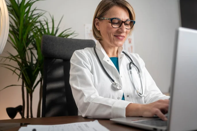 Female doctor working on laptop computer at doctor's office. writing prescripstion, recording patient's information, healthcare and medicine concept