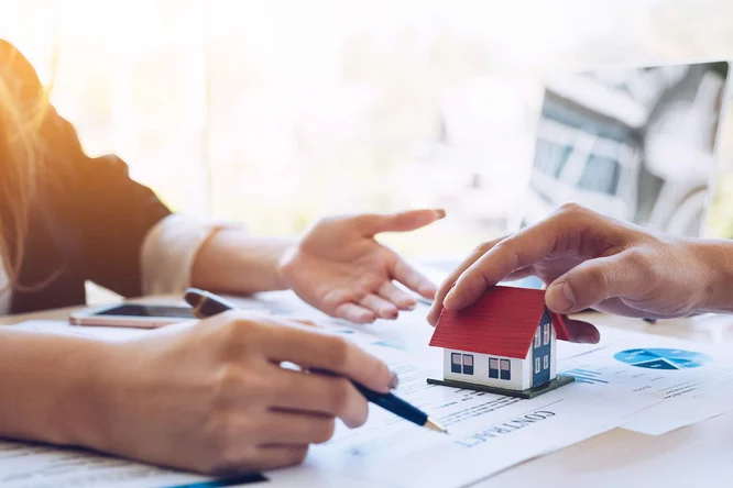 Hände, die über Immobilien mit einem Hausmodell diskutieren