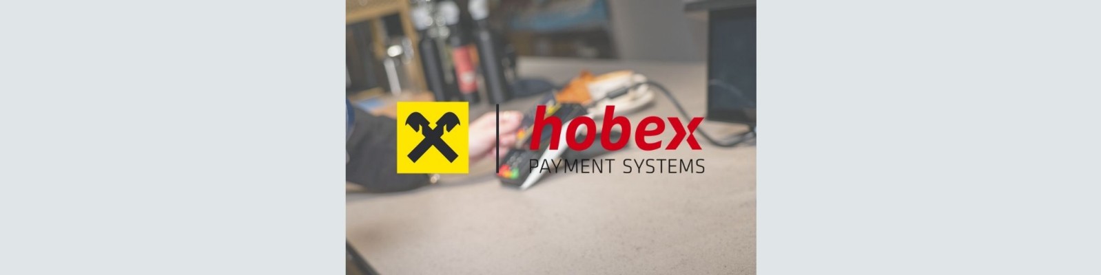 Symbolbild Raiffeisen-Logo und hobex-Logo im Vordergrund im Hintergrund wird mit Kreditkarte bezahlt