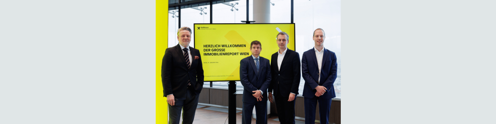 4 Personen posieren vor einem Bildschirm mit einer Präsentation zum Thema Immobilienmarkt 