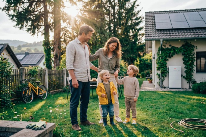 Familie steht im Garten, dahinter Dach mit Solaranlage